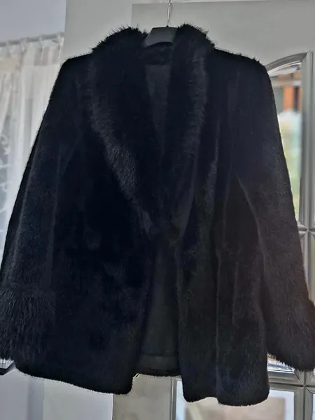 Chaqueta de pelo negra colgada junto a una ventana del taller