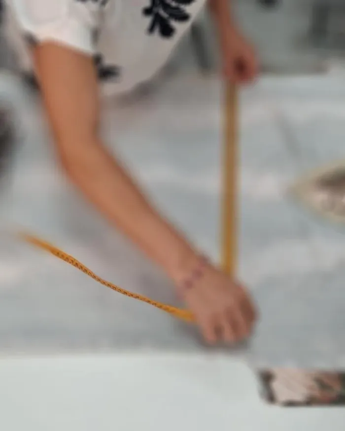 Costurera marcando una tela con tiza de sastre en el taller